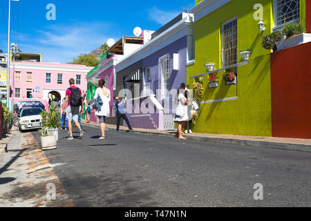 Turistica prendendo la foto in strada di amici in piedi al di fuori di case colorate di Bo Kaap a Cape Malay storico quartiere residenziale di Cape Town Foto Stock