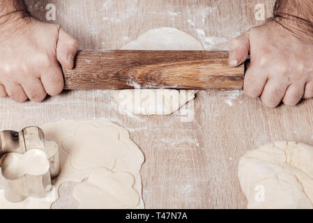 Maschio di rotoli di cucinare la pasta con il matterello, mani closeup Foto Stock