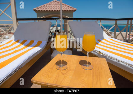 Due cocktail alla frutta Bevande con lettini per prendere il sole sul patio terrazza estiva con vista sul mare Foto Stock