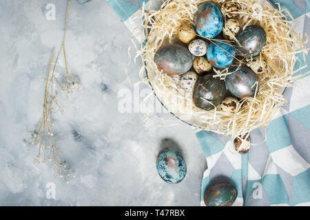 Quaglia e gallina uova dipinte su sfondo di calcestruzzo. Decorazioni di pasqua. Vista superiore e spazio di copia Foto Stock