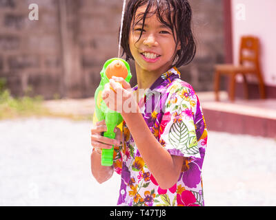 10 anno vecchia ragazza celebrando Songkran, l'annuale festival dell'acqua, pronto per irrorare qualsiasi bypasser qui con pistola ad acqua. Songkran, che è il tradizionale Foto Stock