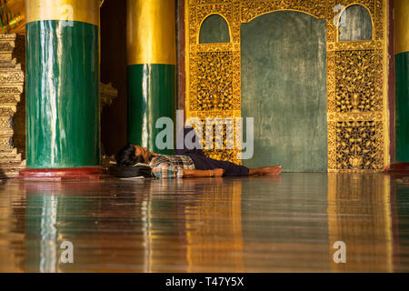 Yangon, Myanmar - 19 Settembre 2016: uomo di dormire sul pavimento di un padiglione all'interno di Shwedagon pagoda complessa Foto Stock