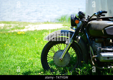 Il Soviet Dnepr motociclo sull'erba verde della parte anteriore vicino fino contro il litorale di sabbia in riva al lago Foto Stock