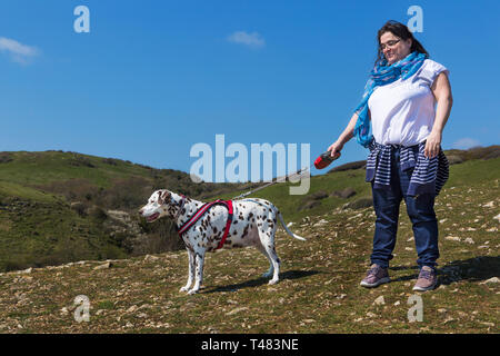 Donna con cane dalmata godendo la vista dalla Durlston Country Park, Swanage, Dorset, Regno Unito in aprile Foto Stock