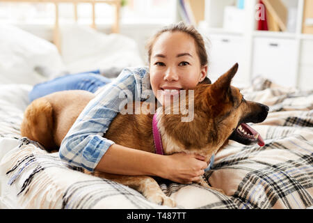 Donna asiatica abbracciando il cane Foto Stock
