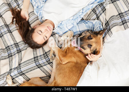 Donna asiatica giacente sul letto con il cane Foto Stock