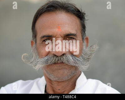 Di mezza età di Rajasthani indiano uomo con un arancione tilaka mark e amichevole costolette di montone pone per la fotocamera. Foto Stock