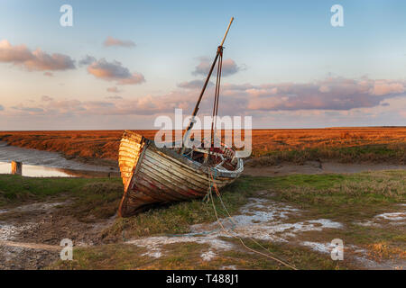 Un vecchio spiaggiata barca da pesca su paludi a Thornham sulla costa di Norfolk Foto Stock