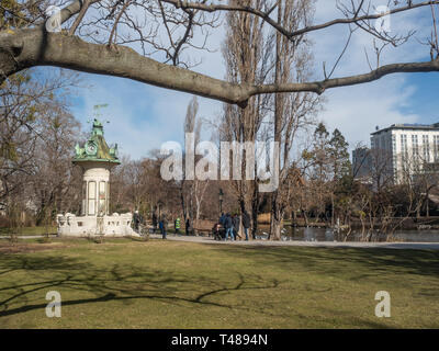 Vienna, Austria, 23 febbraio 2019. La gente a piedi attraverso Stadtpark con una piccola torre dell orologio Foto Stock