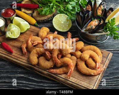 Panate i gamberetti, cozze servite con calce sulla tavola di legno, delizioso, profondo rosso, la salsa bianca Foto Stock