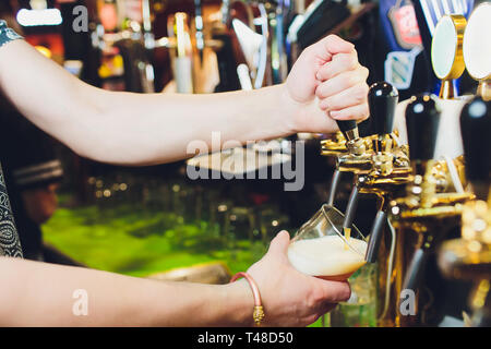 Siamo in grado di soddisfare l'Oktoberfest. Mano del barista versando una grande birra lager in tap. Versare birra per client. Vista laterale del giovane barista versare birra mentre Foto Stock