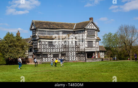 Famiglia godendo di una giornata a Little Moreton Hall, bianco e nero maniero Tudor a graticcio vicino Congleton a Cheshire, di proprietà della fiducia nazionale Foto Stock