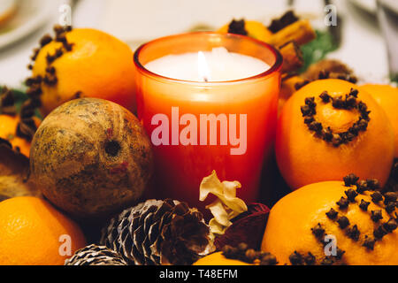 Decorazione di Natale candela set, con pigne e arance decorate con chiodi di garofano, su un tavolo per la cena. Foto Stock