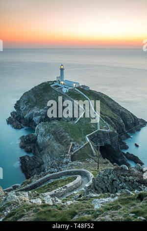 In prima serata la scena al tramonto guardando il mare verso sud pila faro, Anglesey, Galles del Nord. Foto Stock