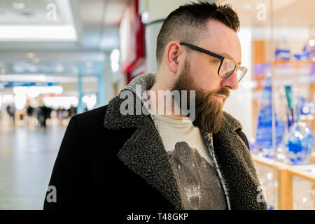 Maschio bianco con gli occhiali su cavalletti e guarda a prodotti in aeroporto internazionale di Praga - Repubblica Ceca Foto Stock