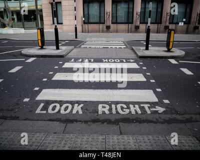 Un crosswalk a Londra avverte i pedoni a guardare a destra per i veicoli che sopraggiungono in senso contrario Foto Stock