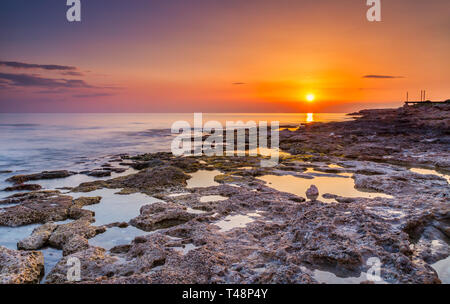 Tramonto lungo la splendida costa rocciosa vicino a Paphos sulla costa occidentale dell'isola di cipro. Foto Stock