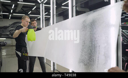 Pellicola per auto incollando. Costosa auto incollando il film. Elite film per incollare le automobili. Incollaggio di auto wrap vinile adesivo in plastica carbonico closeup Foto Stock