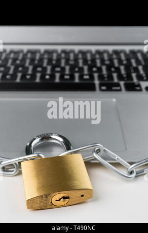 Il lucchetto e catena con computer portatile su uno sfondo bianco. Cyber security concetto astratto. Orientamento verticale. Foto Stock