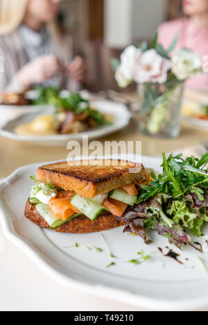 French Toast brioche, panini con salmone e cetriolo. Luce prima colazione al mattino, freschi pasticcini caldi sul tavolo nel ristorante Foto Stock