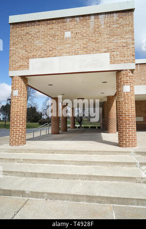 Passi concreti che conduce fino a un entrata coperta per una scuola moderna, l'edificio è fatta di mattoni e ci sono rotonde colonne di mattoni dall'area coperta Foto Stock