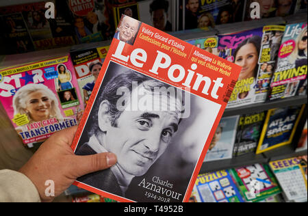 MONTREAL, Canada - 9 ottobre 2018: Le Point magazine con Charles Aznavour sul coperchio anteriore in una mano sopra una pila di caricatori. Le Point è un Fren Foto Stock