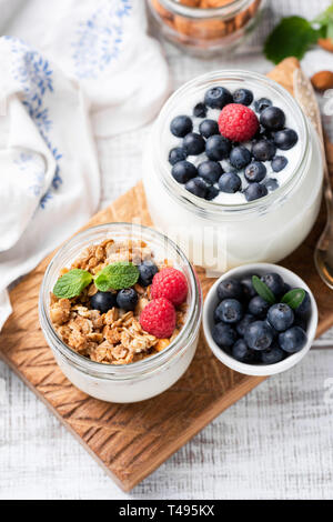 Muesli, mirtilli e lamponi e yogurt nel barattolo sulla tavola di legno. Vista superiore Foto Stock