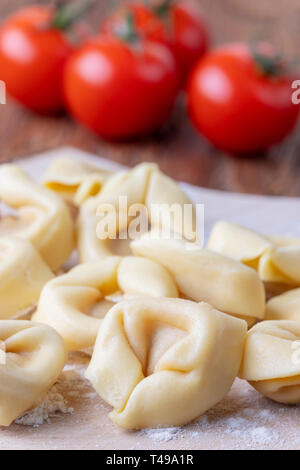 Materie tortellini su legno con pomodori Foto Stock