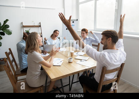 Entusiasti di business diversi team festeggiare il successo si siedono a tavola Foto Stock