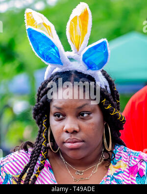 Una donna indossa bunny orecchie durante una comunità uovo di Pasqua Caccia al Langan Park, 13 aprile 2019, nel Mobile, Alabama. Foto Stock