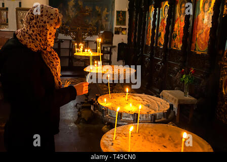 Donna accendere una candela nella parte anteriore delle icone in un tempio ortodosso;la Bulgaria; Foto Stock