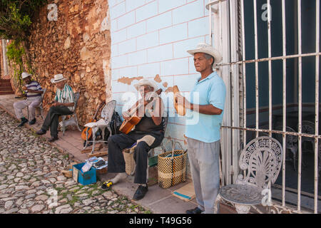 TRINIDAD CUBA Luglio 2 2012; musicisti in village street con la chitarra seduti e in piedi nella parte anteriore della parete con peeling paint giocando per turisti. Foto Stock