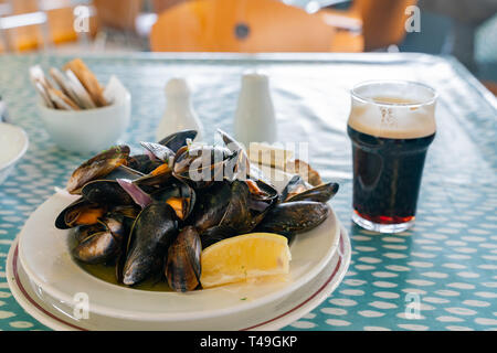 Immagine ravvicinata di un bicchiere di birra scura e un piatto di cozze a Galway, Irlanda Foto Stock
