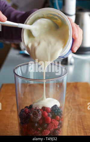 Frutta estiva fresca e crème fraiche essendo aggiunto a un frullatore a immersione per rendere un frullato di frutta Foto Stock