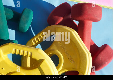 Una selezione di casa attrezzature da palestra su un colorato materassino yoga Foto Stock