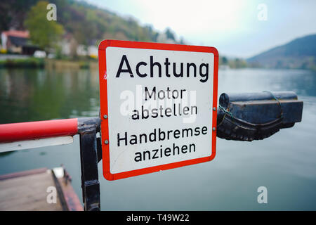 08 aprile 2019, Baden-Wuerttemberg, Neckargemünd: una barriera e un cartello con la scritta "Attenzione. Spegnere il motore. Tirare il freno a mano." si trova a bordo di un traghetto sul fiume Neckar tra Neckarhausen e Neckarhäuserhof. (A DPA: 'traghettatore di anime tra gli stati federali - giovane talento preoccupazioni risolto' del 15.04.2019) Foto: Uwe Anspach/dpa Foto Stock