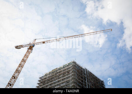 Hannover, Germania. Xi Apr, 2019. Le nuvole si muovono su di una gru da cantiere e di un edificio in costruzione. Credito: Moritz Frankenberg/dpa/Alamy Live News Foto Stock