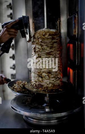 Shwarma fresca fatta sul grill e grill l uomo è il taglio del Shwarma per servire. Foto Stock
