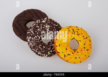 Ciambelle assortiti con cioccolato smerigliati, giallo smaltati e spruzza le ciambelle. Dolce e colorata bomboloni Foto Stock