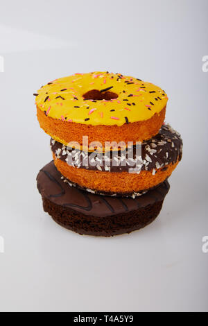 Ciambelle assortiti con cioccolato smerigliati, giallo smaltati e spruzza le ciambelle. Dolce e colorata bomboloni Foto Stock