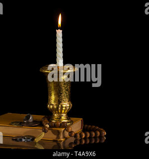 Candela con rosario, libri antichi e monete Foto Stock