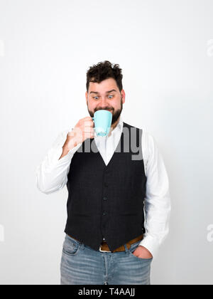 Bello, giovane con barba nera in posa con il turchese tazza di caffè o di tè cup davanti a uno sfondo bianco e produrre diverse espressioni del viso Foto Stock