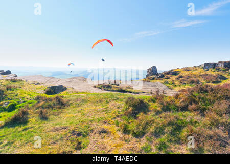 Due parapendii salire oltre il bordo Curbar nel Derbyshire Disrtict picco su un vago giornata di primavera. Foto Stock