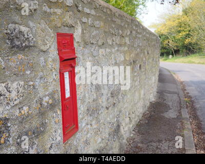 15 apr 2019. Postbox rosso nel vecchio muro di pietra in Forest Hill, Oxfordshire, Regno Unito. Foto Stock