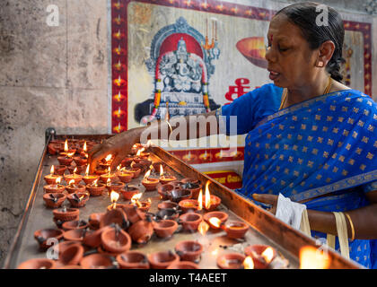 Posizione orizzontale Ritratto di signora di illuminazione un olio lampada a un tempio in India. Foto Stock