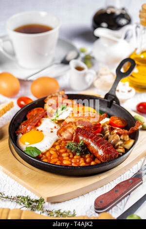 La completa prima colazione inglese inclusa salsicce, pomodori grigliati e funghi, uova, bacon e fagioli al forno Foto Stock