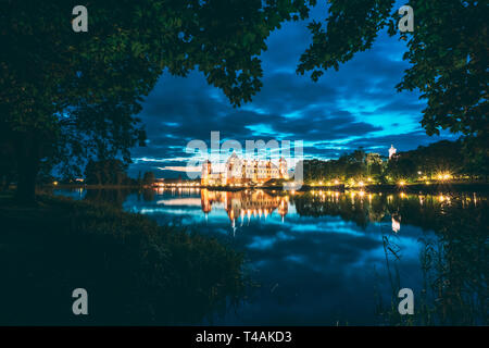 Mir, Bielorussia. Notte Vista panoramica del Castello di Mir In illuminazione serale con candelette di riflessioni sul lago di acqua. UNESCO - Sito Patrimonio dell'umanità. Famoso punto di riferimento Foto Stock