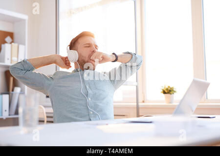 Giovane uomo sbadigliare al lavoro Foto Stock