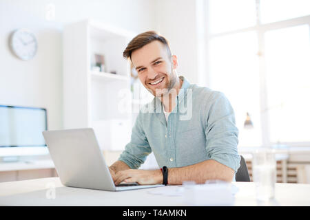 Sorridente giovane uomo utilizzando Laptop Foto Stock