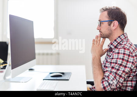 Sottolineato imprenditore seduto al computer desktop in ufficio. Foto Stock